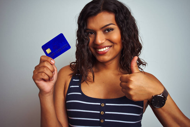Transsexual transgender customer woman holding credit card over isolated white background happy with big smile doing ok sign, thumb up with fingers, excellent sign - Valokuva, kuva