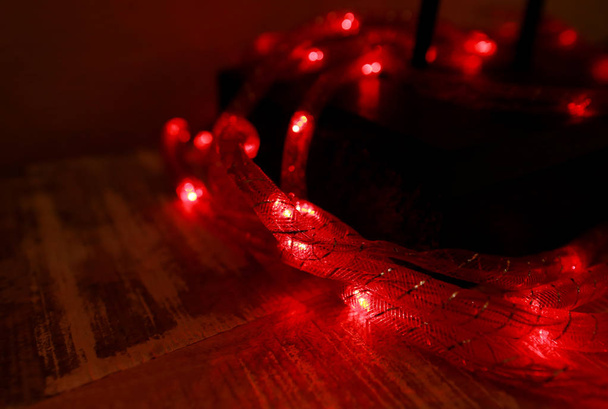 Parlak kırmızı yeni yıl ışıkları ve noel pirinç ışıkları, sığ alan derinliği. Soyut kırmızı ışık arkaplanı. Dekoratif yanıp sönen ışıklar, Noel kutlaması için süsler, tatil sahneleri. Noel konsepti. - Fotoğraf, Görsel