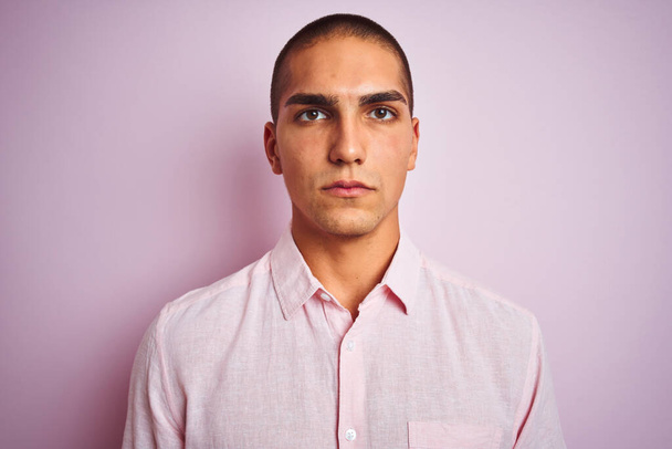 Young handsome man wearing elegant shirt over pink isolated background with a confident expression on smart face thinking serious - Fotografie, Obrázek