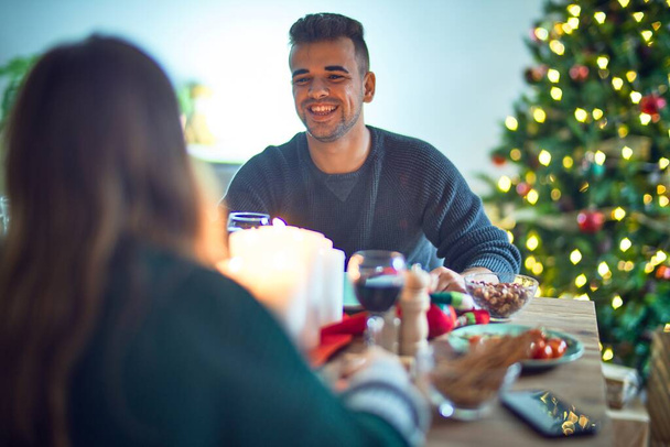 Nuori kaunis pari hymyilee onnellisena ja itsevarmana. Syöminen ruokaa juhlii joulua kotona
 - Valokuva, kuva