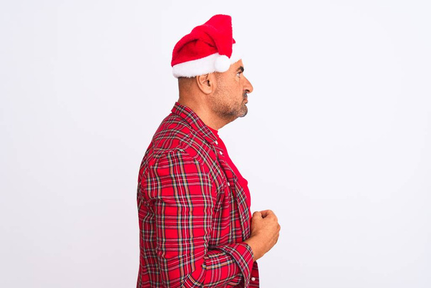 Keski-ikäinen mies yllään joulupukki hattu seisoo yli eristetty valkoinen tausta etsii sivuun, rentoutua profiili aiheuttaa luonnolliset kasvot luottavainen hymy
. - Valokuva, kuva