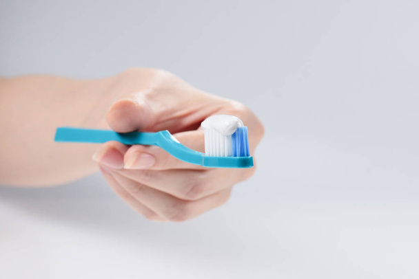 Mujer sostiene cepillo de dientes con pasta de dientes en su mano aislado en w
 - Foto, Imagen