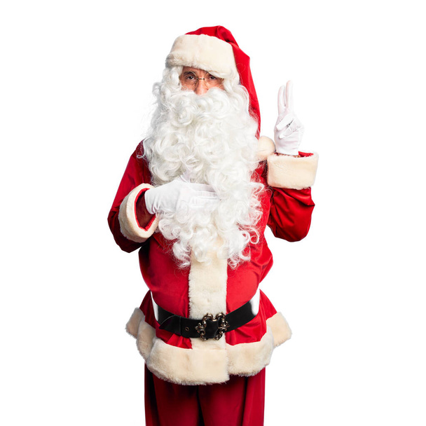 Orta yaşlı yakışıklı adam, Noel Baba kostümü ve sakal takmış, gülümsüyor, elleri göğsünde ve parmakları havada, sadakat yemini ediyor. - Fotoğraf, Görsel
