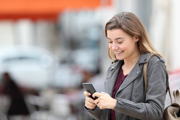 Joyeux adolescent textos sur téléphone portable marche dans la rue
 - Photo, image