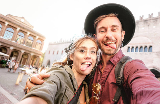 Happy boyfriend and girlfriend in love having genuine fun taking selfie at old town tour - Wanderlust life style travel vacation concept with tourist couple on city sightseeing - Bright warm filter - Photo, Image