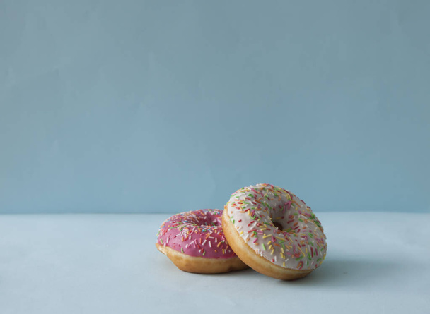Delicious doughnuts with sprinkles on color background - Fotoğraf, Görsel