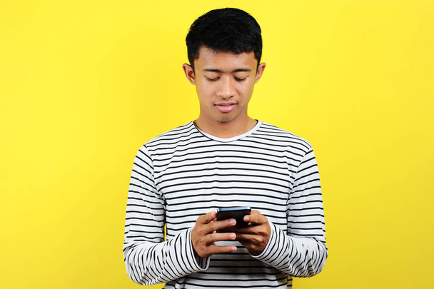 feliz jovem bom olhar asiático homem sorrindo usando smartphone
 - Foto, Imagem