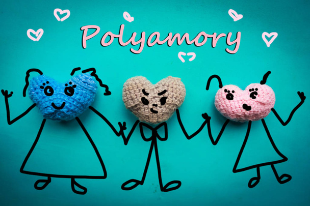 Three knitted hearts with draw faces hold hands - polyamory concept - Photo, Image