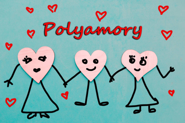 Three wooden hearts with draw faces hold hands - polyamory concept - Photo, Image