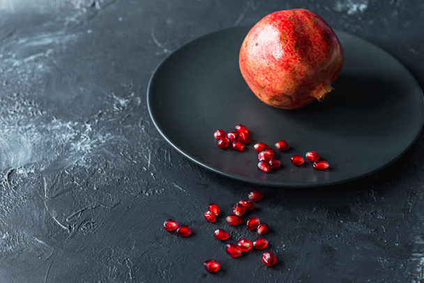 reifer roter Granatapfel und Korn auf grauem Hintergrund - Foto, Bild