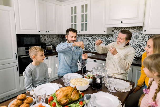 hermosa familia feliz celebrando el día de acción de gracias juntos. Padre abre una botella de vino tinto, el abuelo se ríe
 - Foto, imagen
