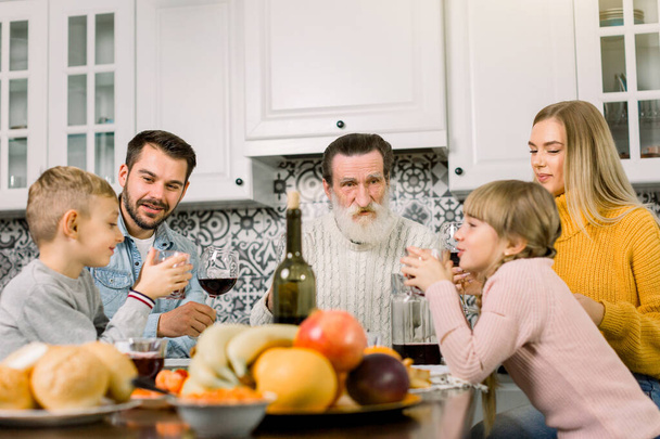 Több generációs család ünnepli a hálaadást, együtt ülnek az asztalnál a modern világos étkezőben. Nagyapa, szülők és két kisgyermek - Fotó, kép