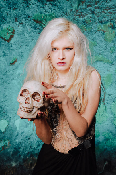 hermosa mujer con peinado rubio. adulto delgada chica con el cráneo de Halloween en las manos. luz mística
. - Foto, imagen