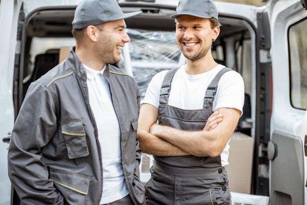 Porträt zweier Mitarbeiter einer Lieferfirma, die Waren mit dem Auto ausliefern - Foto, Bild