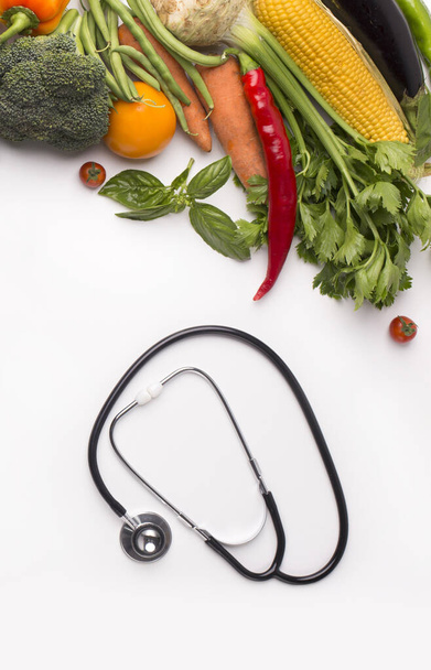 Stéthoscope et collecte de légumes frais sur blanc
 - Photo, image