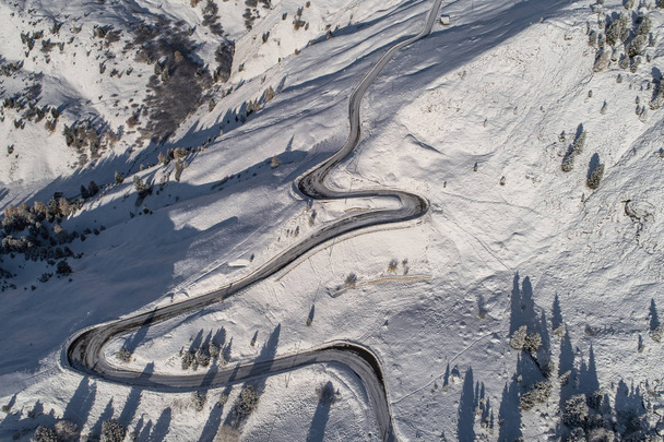 Curved road in the Italian Alps in South Tyrol, during winter / Sunny winter day with harsh shadows and lot of snow - Fotografie, Obrázek