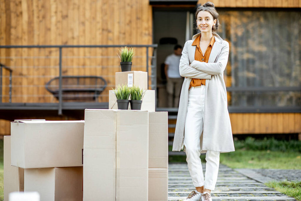Donna con scatole davanti a una nuova casa
 - Foto, immagini
