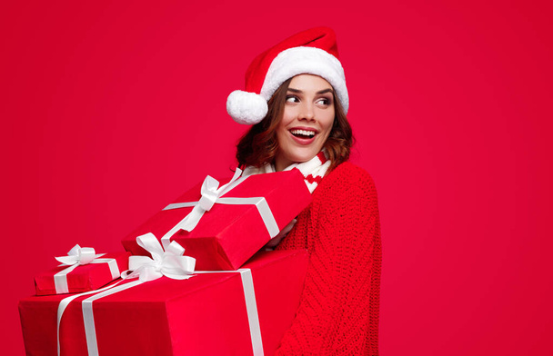 Content woman in Santa hat carrying wrapped presents - Fotó, kép