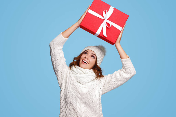 Excited woman holding wrapped present above head - Foto, Imagen