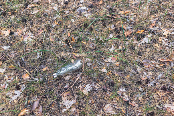 Fehér műanyag palack a földön egy fenyőerdőben. - Fotó, kép