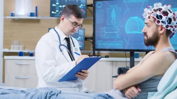 Doctor in brain research staying next to patient bed and taking notes on clipboard - Footage, Video