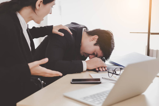 Businessman or colleagues guy sleeping during working with businesswoman. Workmate woman trying to wake up him but he still sleeping on desk at office. She get frustrated, unhappy, angry with lazy guy - Photo, Image