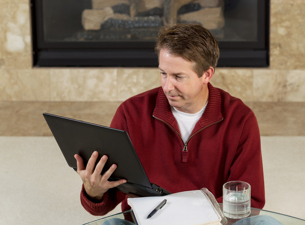 Homme mûr lisant des informations de son ordinateur alors qu'il était à la maison
 - Photo, image