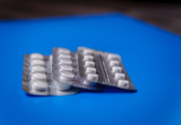 The blister packs are folded. Pills in a blister pack on a blue background. - Photo, Image