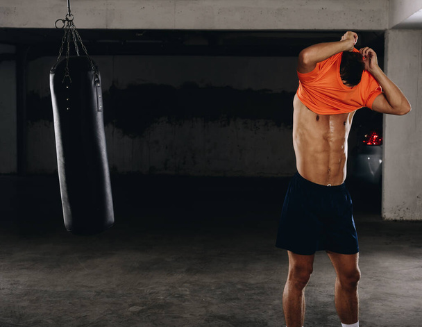 ein hübscher junger Sportler zieht sich nach dem Boxtraining um - Foto, Bild