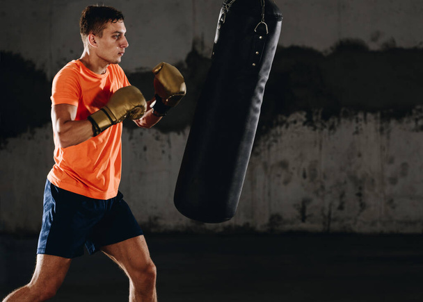 Um boxeador silhueta a bater num saco enorme num estúdio de boxe. homem boxer formação duro
 - Foto, Imagem