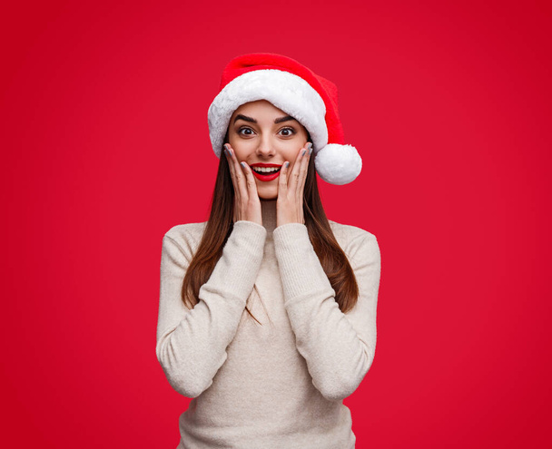 Surprised woman in Santa hat and sweater - Фото, изображение