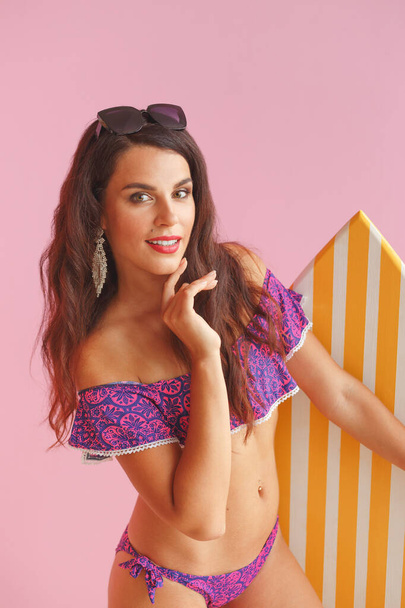 Girl in swimwear with surfboard isolated on pink background - Photo, image