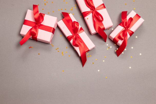 Cajas de regalo sorpresa artesanal de Navidad con cintas rojas y estrellas doradas brillan sobre fondo gris, vista superior. Año Nuevo
. - Foto, Imagen