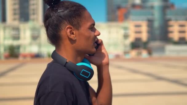 puolella näkymä hipster kaveri kuulokkeet on puhelin keskustelu kävelee kaupungissa
 - Materiaali, video