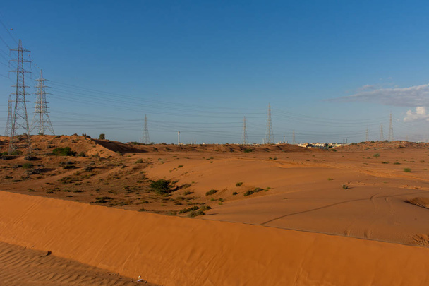 Chmurny, ale słoneczny wieczór z widokiem na pomarańczowy pustynny piasek w Ras al Khaimah, Zjednoczone Emiraty Arabskie w zimie. Kemping Dune, biczowanie, atv, obszar. Koncepcja pustyni. - Zdjęcie, obraz
