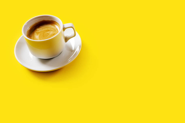 Black coffee in a cup on a yellow background - Фото, зображення