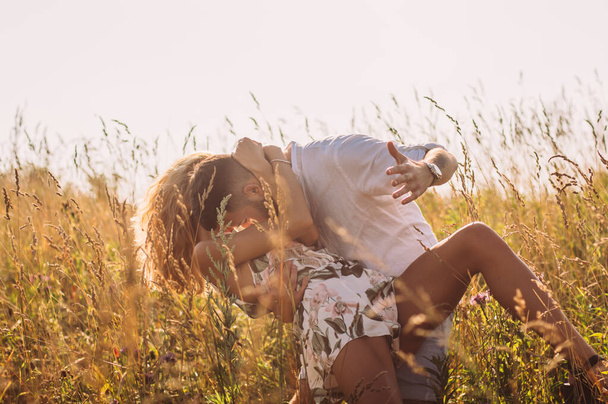 Young man hugging and kissing his girlfriend in the field - Fotografie, Obrázek