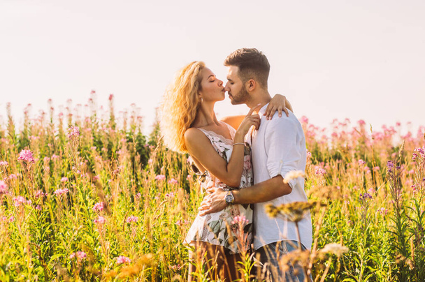 Молодой человек обнимает и целует свою девушку в поле
 - Фото, изображение