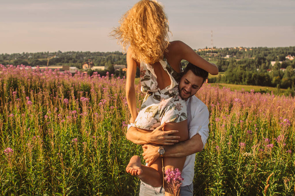 Young man carry his girlfriend on hands in the field - 写真・画像