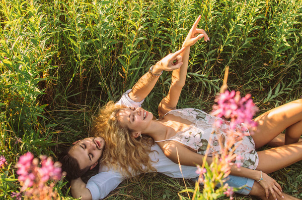 jonge vrouw ligt op haar vriend en dwaalt rond in het veld - Foto, afbeelding