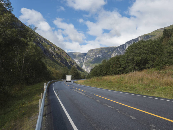 Bílý karavan auto na Winding Road E136 s horským masivem Trolltindene, Troll zeď Trollveggen v Romsdal údolí, Norsko. Modrá obloha bílé mraky. Letní výlet cestovní scenérie. - Fotografie, Obrázek