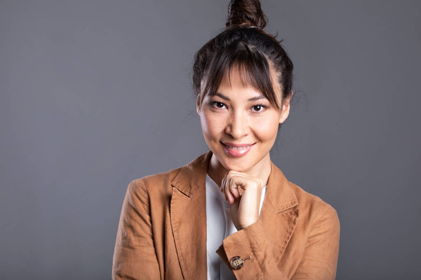 Headshot of happy Asian woman on gray background.  - Foto, afbeelding