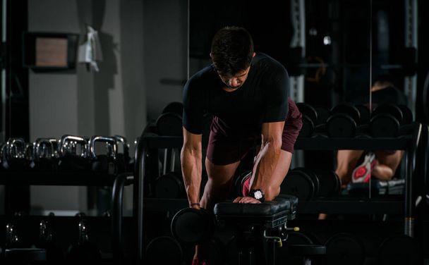 Slim muscular man lifting weights in the gym - Фото, зображення
