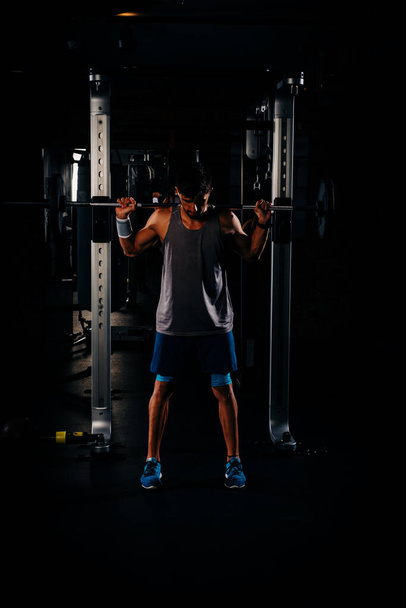 Тонкий м'язистий чоловік, що працює з вагами в спортзалі
 - Фото, зображення