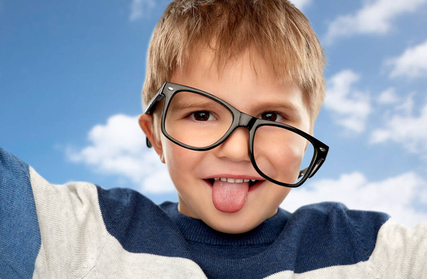 portrait of little boy in glasses showing tongue - Foto, afbeelding