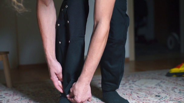 Közelkép, a fickó fém gombokat erősít a nadrágjára. - Felvétel, videó