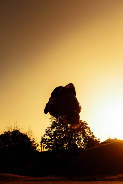 Jonge silhouet man het uitvoeren van een back flip  - Foto, afbeelding