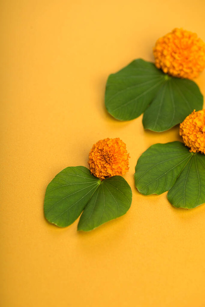 Indian Festival Dussehra, showing golden leaf (Bauhinia racemosa) and marigold flowers on a yellow background. - Photo, image