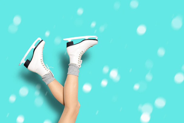 Sexy woman legs wearing ice skates and woolen socks over blue background with snowflakes - Fotoğraf, Görsel