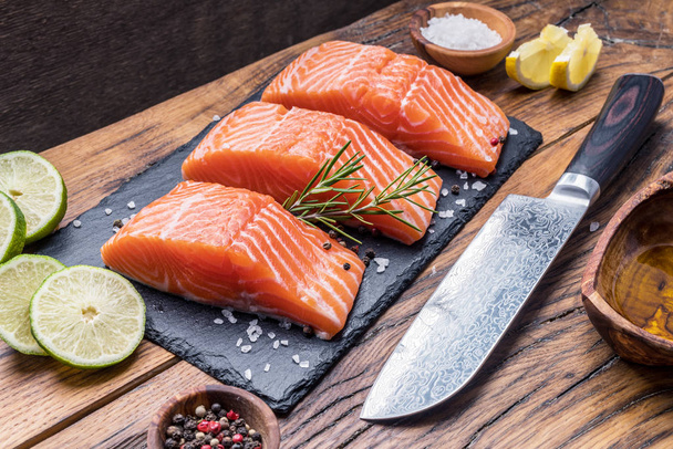 Fresh salmon fillets on black cutting board with herbs and spice - Foto, immagini